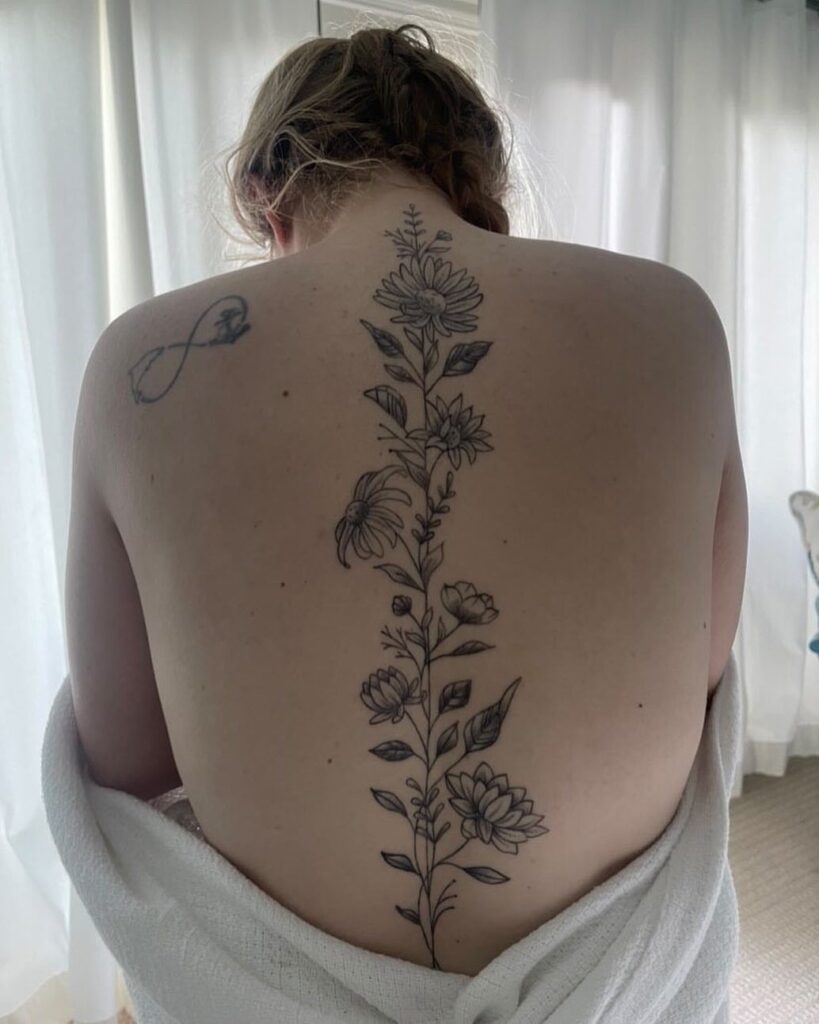 A vertical floral tattoo running down the center of a person's spine.