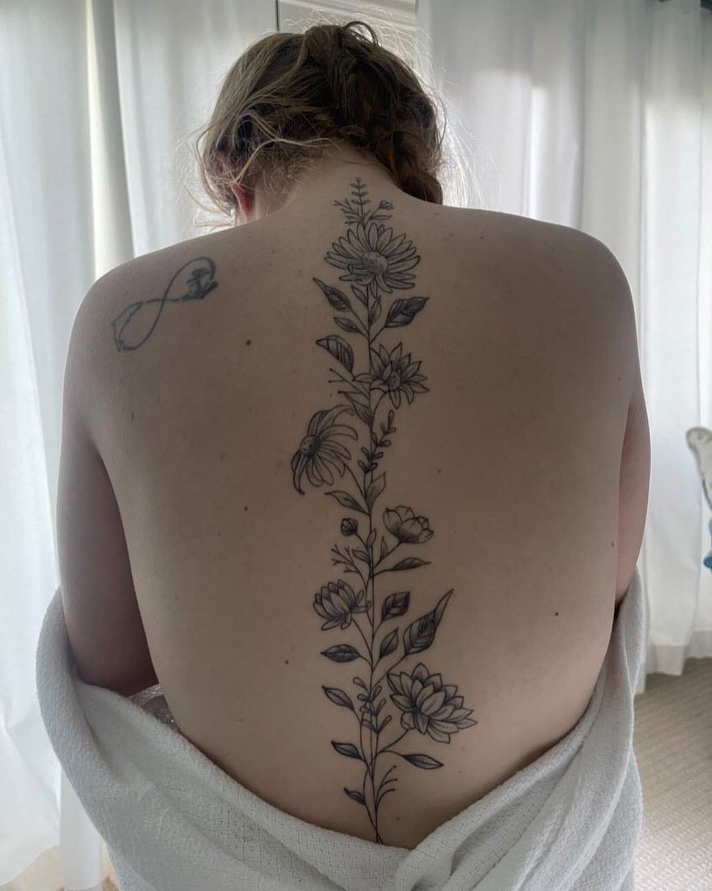 A vertical floral tattoo running down the center of a person's spine.