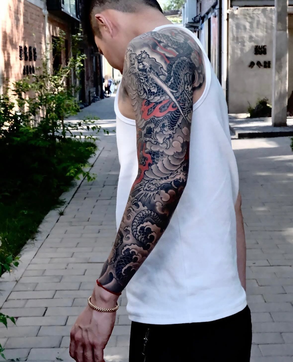 A man's arm featuring a large, detailed Japanese dragon tattoo with wave patterns.