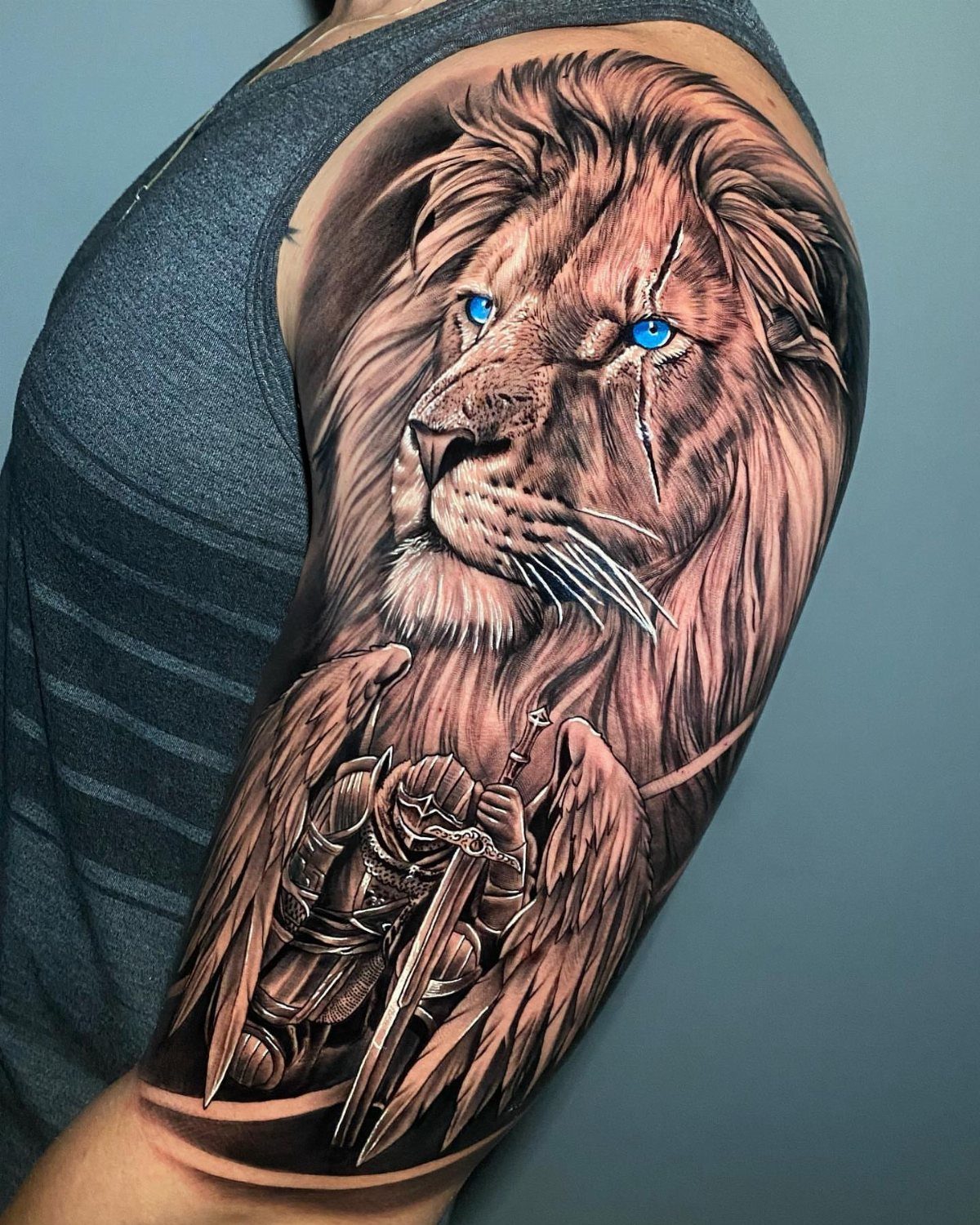 A detailed lion and winged knight tattoo covering a person's shoulder and upper arm.