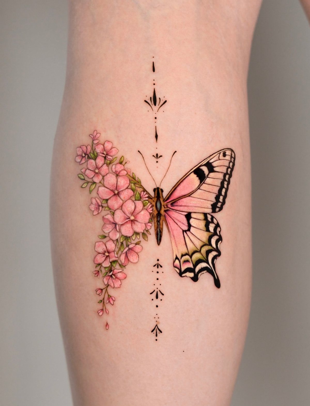 A butterfly tattoo on a leg where one wing is made of pink flowers.
