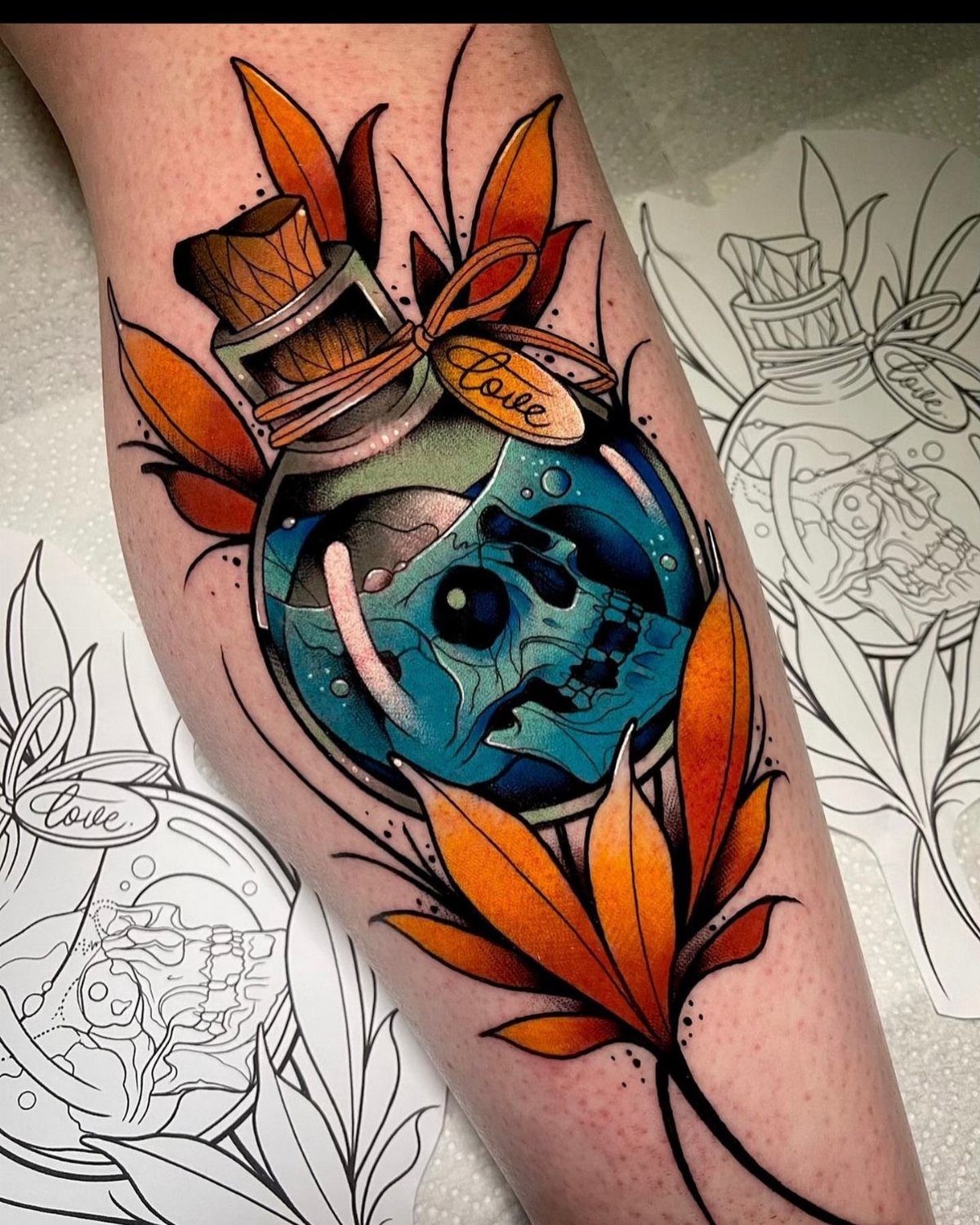 Neo traditional tattoo of a blue skull in a glass bottle with orange leaves on an arm.