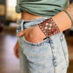 A person's forearm displaying a colorful traditional floral tattoo cuff design.